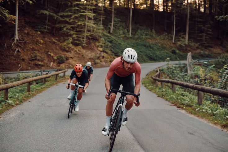 Three road cyclists riding on a forest road at golden hour